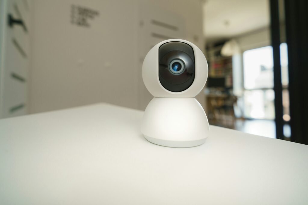 Image of a sleek, modern smart camera placed on a table, featuring a wide-angle lens and LED indicators, designed for home security and remote monitoring.